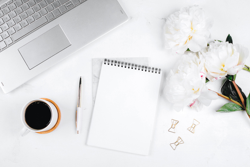 Workplace with Laptop, Coffee, Flowers , Pen and Notebook 